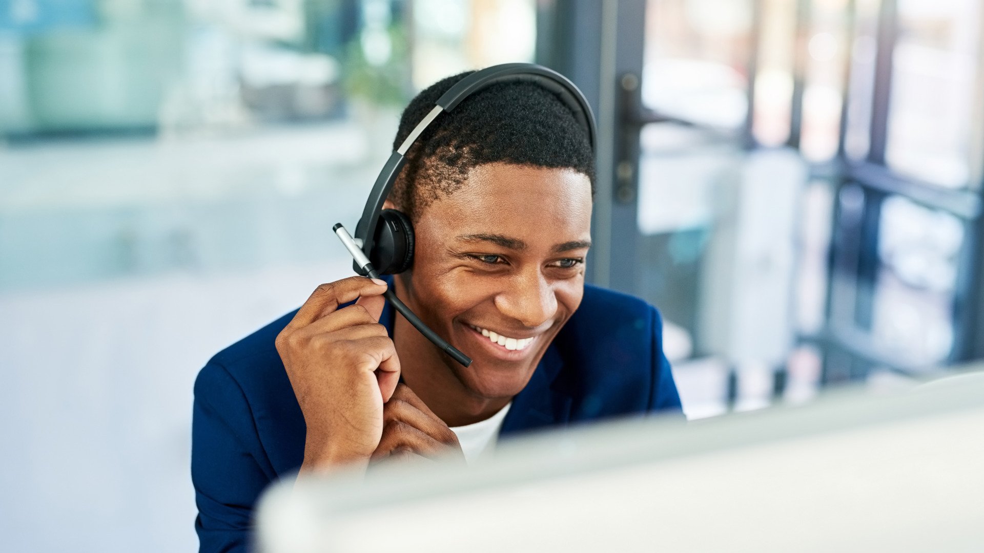 Ein Mitarbeiter telefoniert mit Headset über seinen PC im Büro